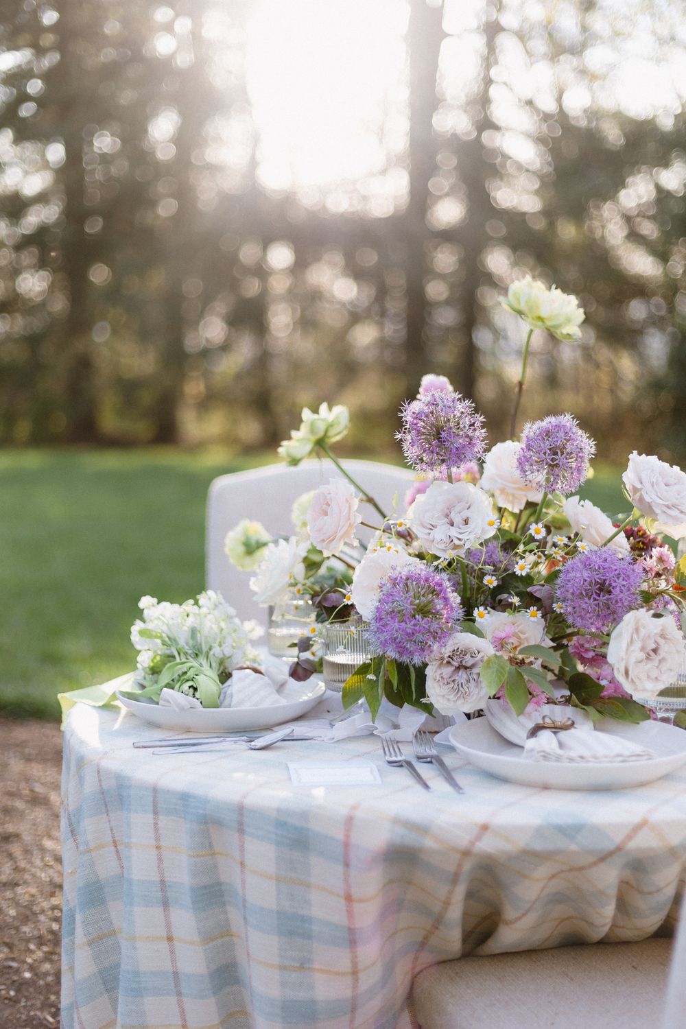 Beautiful purple bouquet sits on a table outside during cocktail hour.