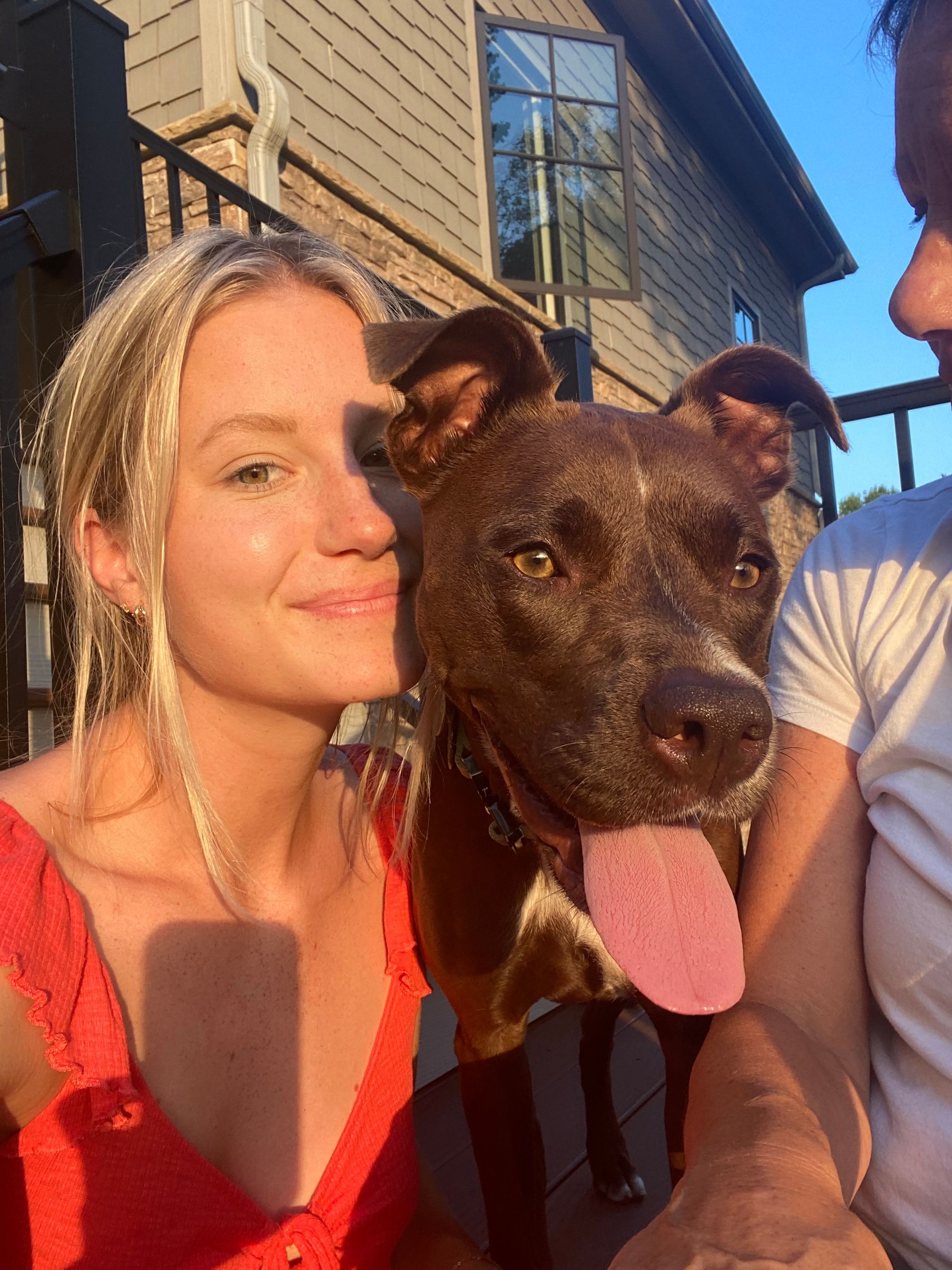 Woman poses with her happy dog while being hit with the natural sunshine.