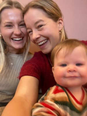 A selfie of two women and a baby girl, laughing at the camera.