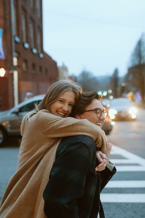 A woman hugs her husband from behind while waiting to cross the street in downtown Asheville.