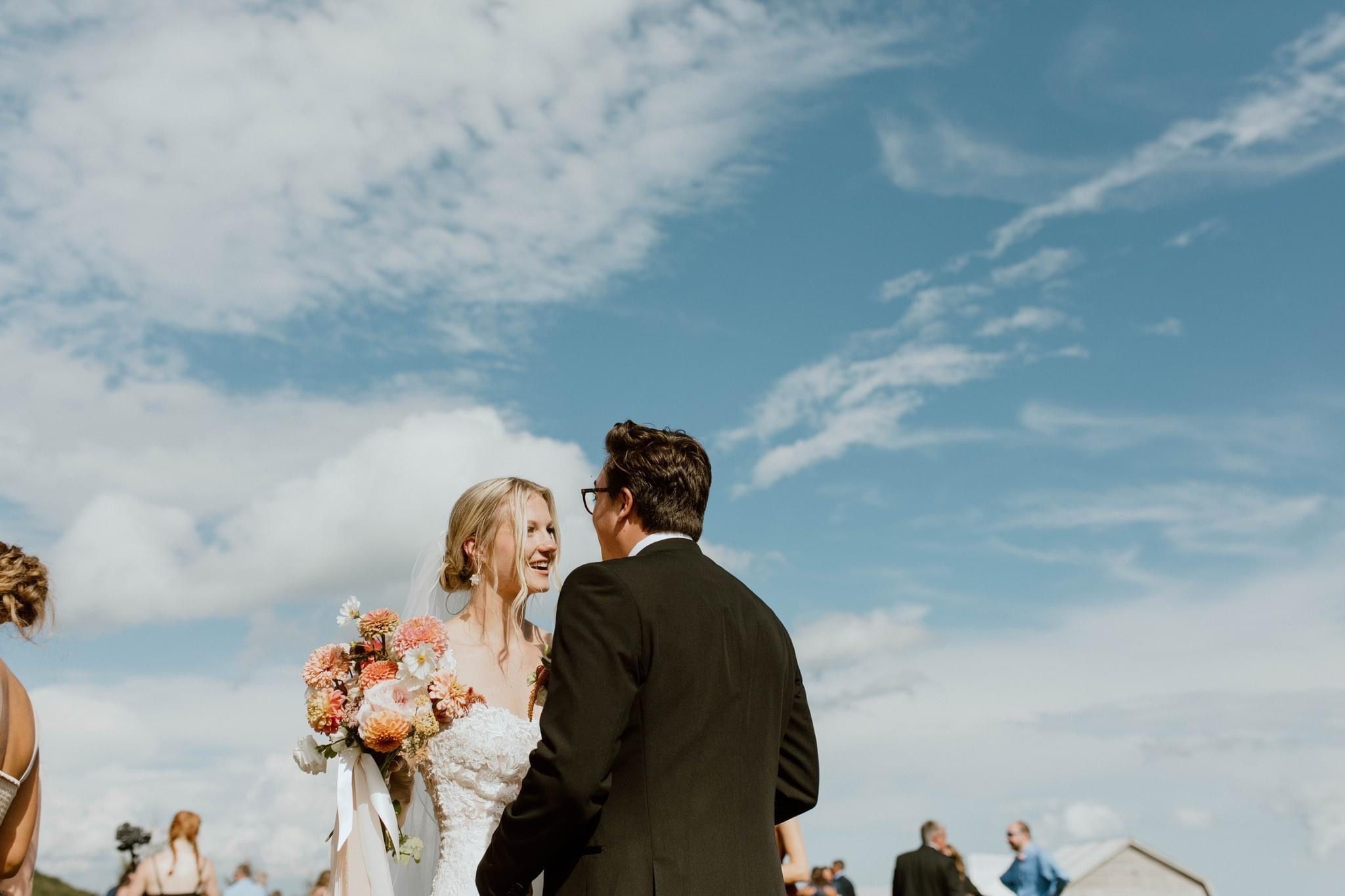 Bride and groom laughing together at Overlook Barn just after their wedding ceremony. Blue skies.