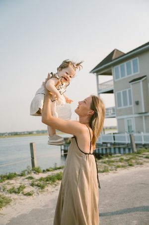 A woman throws her niece up into the air, who is laughing and smiling at the camera.