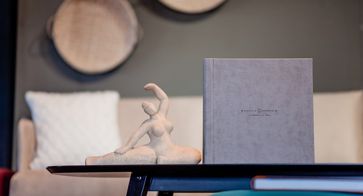 Gray cloth-bound book displayed on shelf with decorative elements in background.