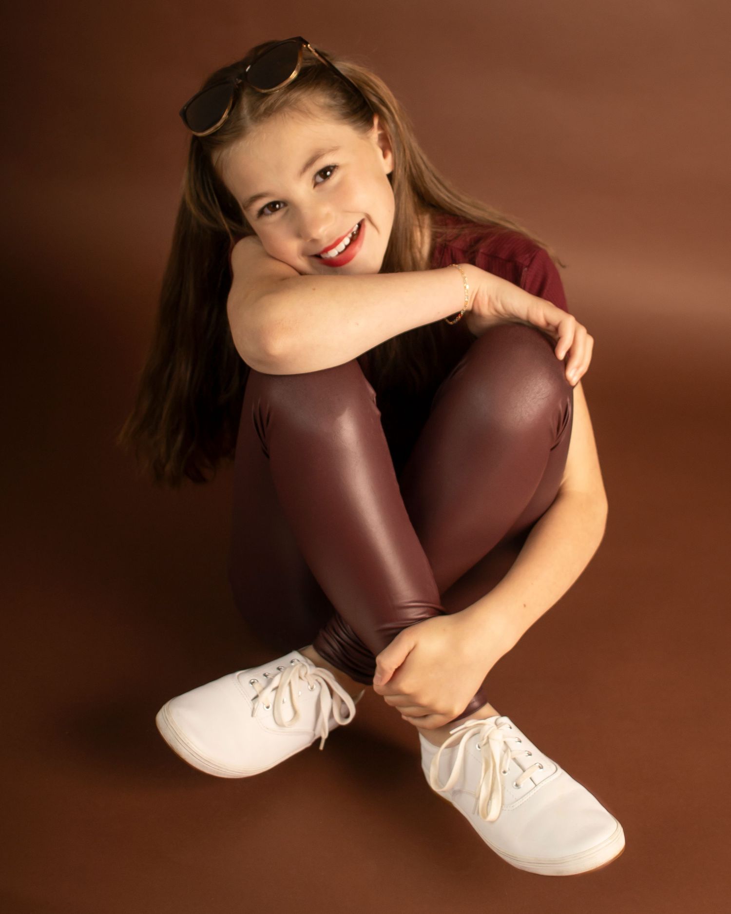 A school age girl smiles at the camera from a twisted seated position