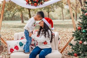 A festive holiday scene with Christmas decorations, a decorated tree and a cozy white armchair surrounded by fallen leaves.