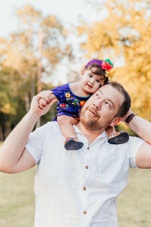 A playful moment outdoors with fall foliage in the background on a sunny autumn day.