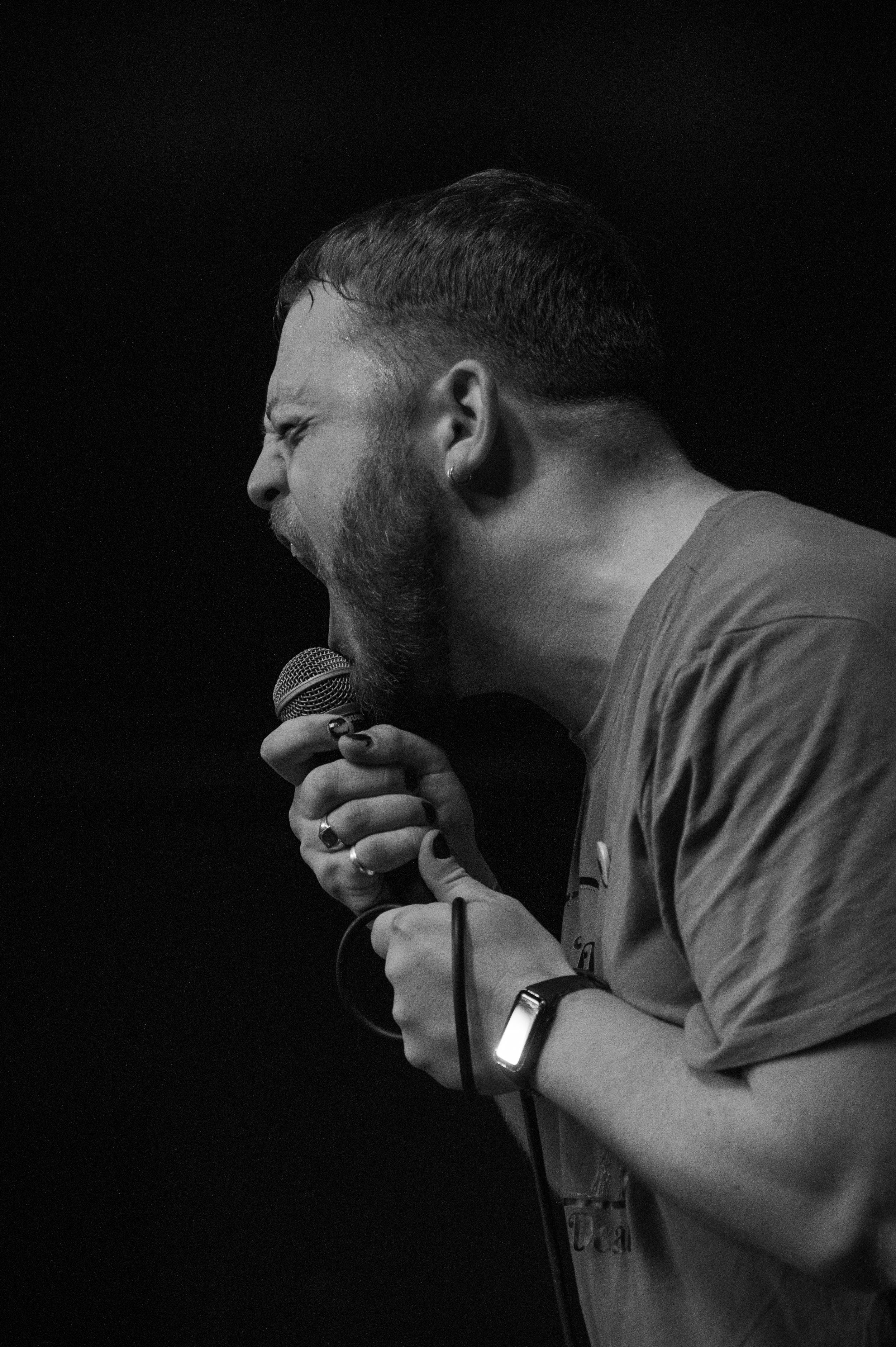 Black and white shot of vocalist singing passionately into microphone during live performance.