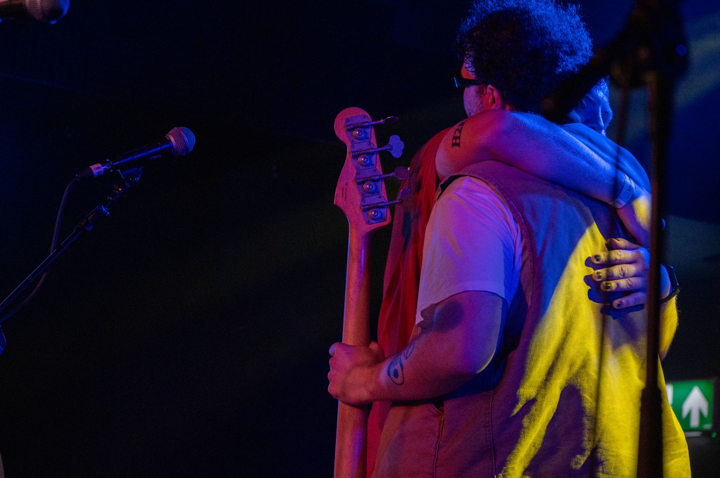 Guitarist silhouetted against colorful stage lighting during live music performance.