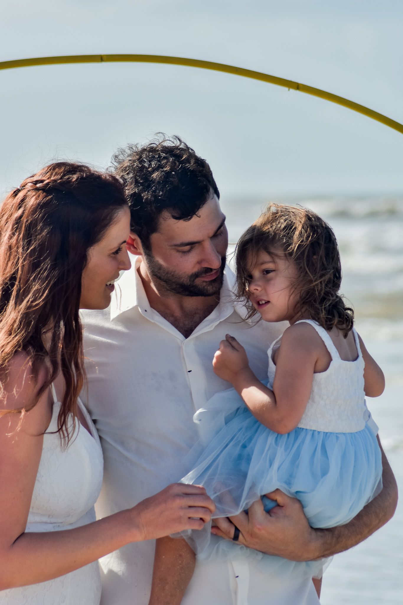 Family shares tender moment together on sunny beach.