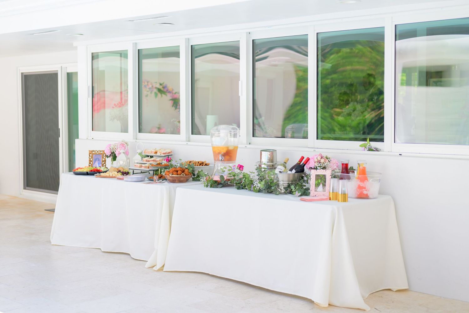 Elegant white buffet tables decorated with colorful floral arrangements and refreshments.