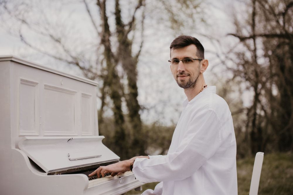 White piano placed outdoors against bare winter trees.