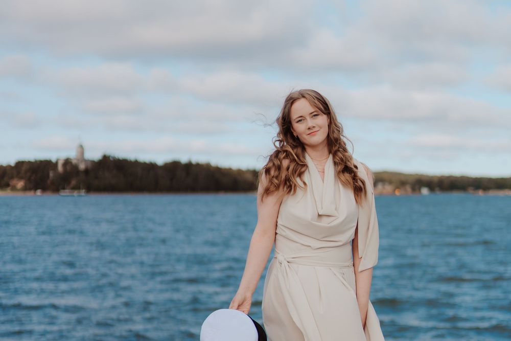 Scenic waterfront photoshoot with flowing dress against blue sky and ocean backdrop.