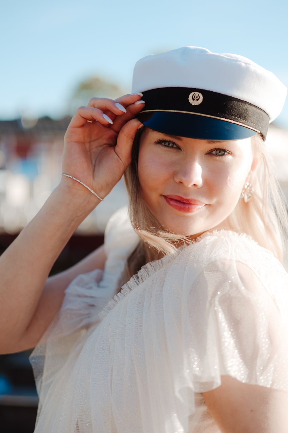 White sailor cap with navy trim against bright blue sky background.