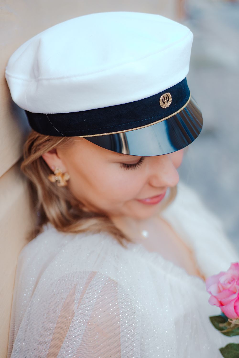 White sailor cap with navy trim worn with delicate lace dress.