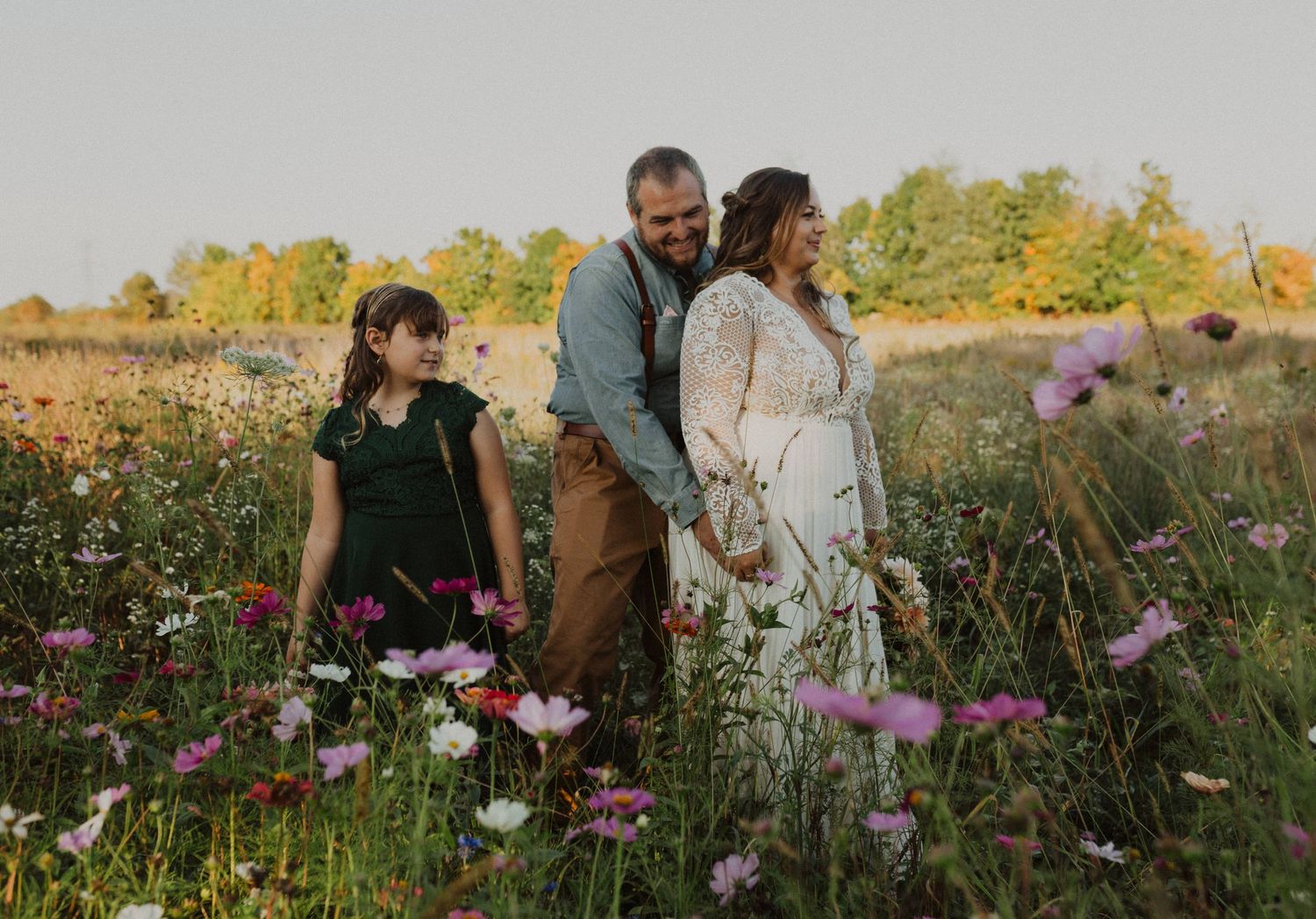 Couple walking through a wildflower field during golden hour sunset.