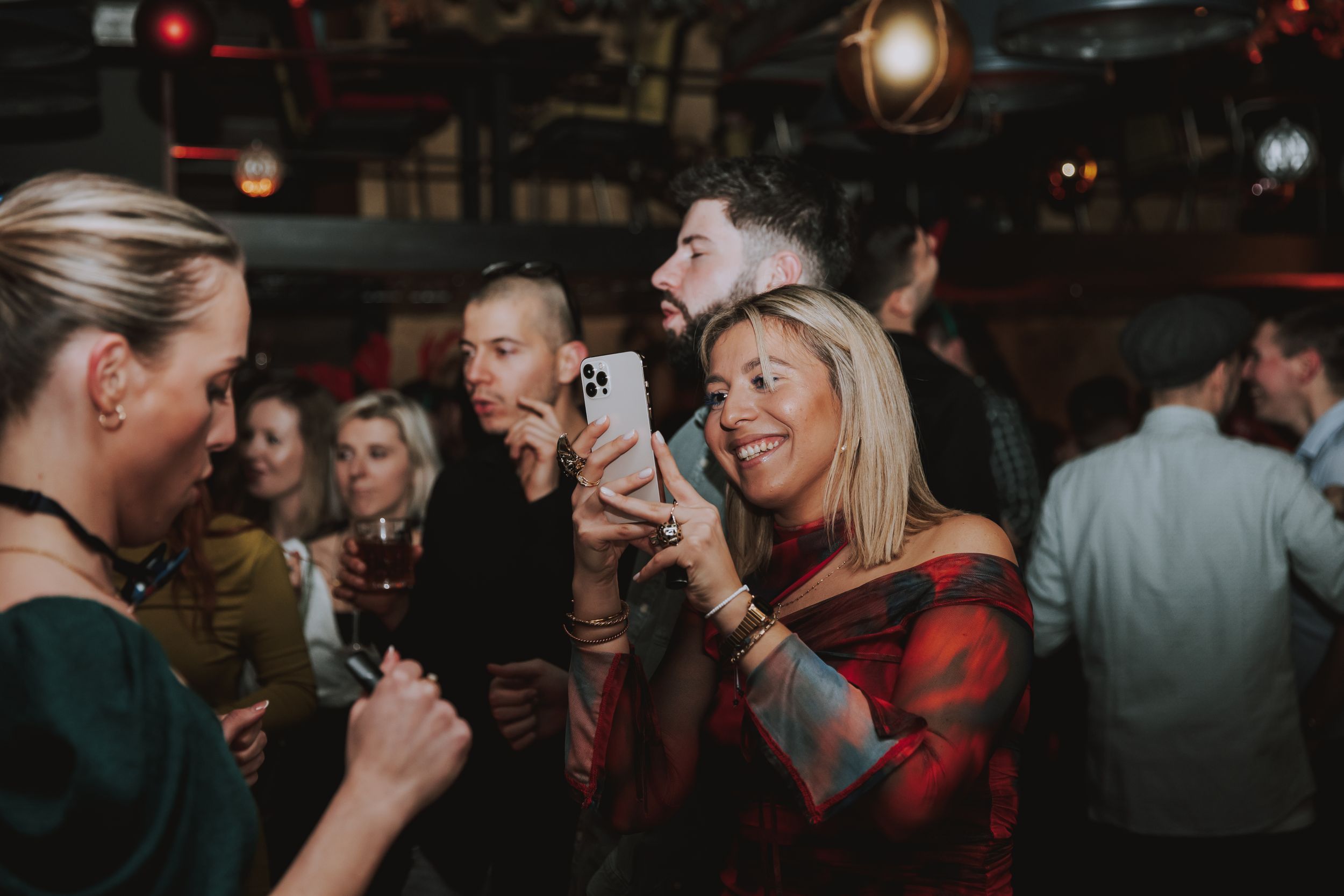 People enjoying drinks and conversation at a lively indoor social gathering.