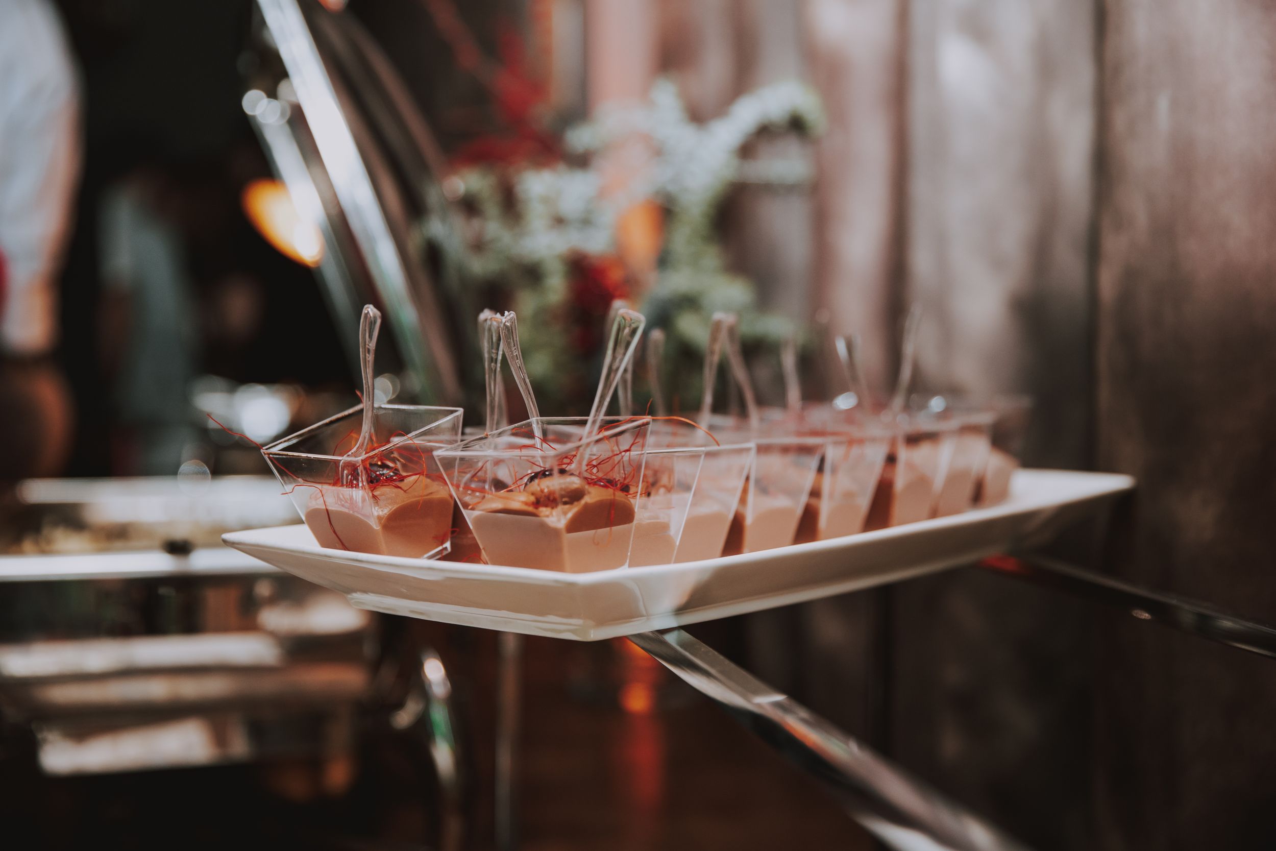 Row of pink cocktails garnished with herbs served on white rectangular platter.