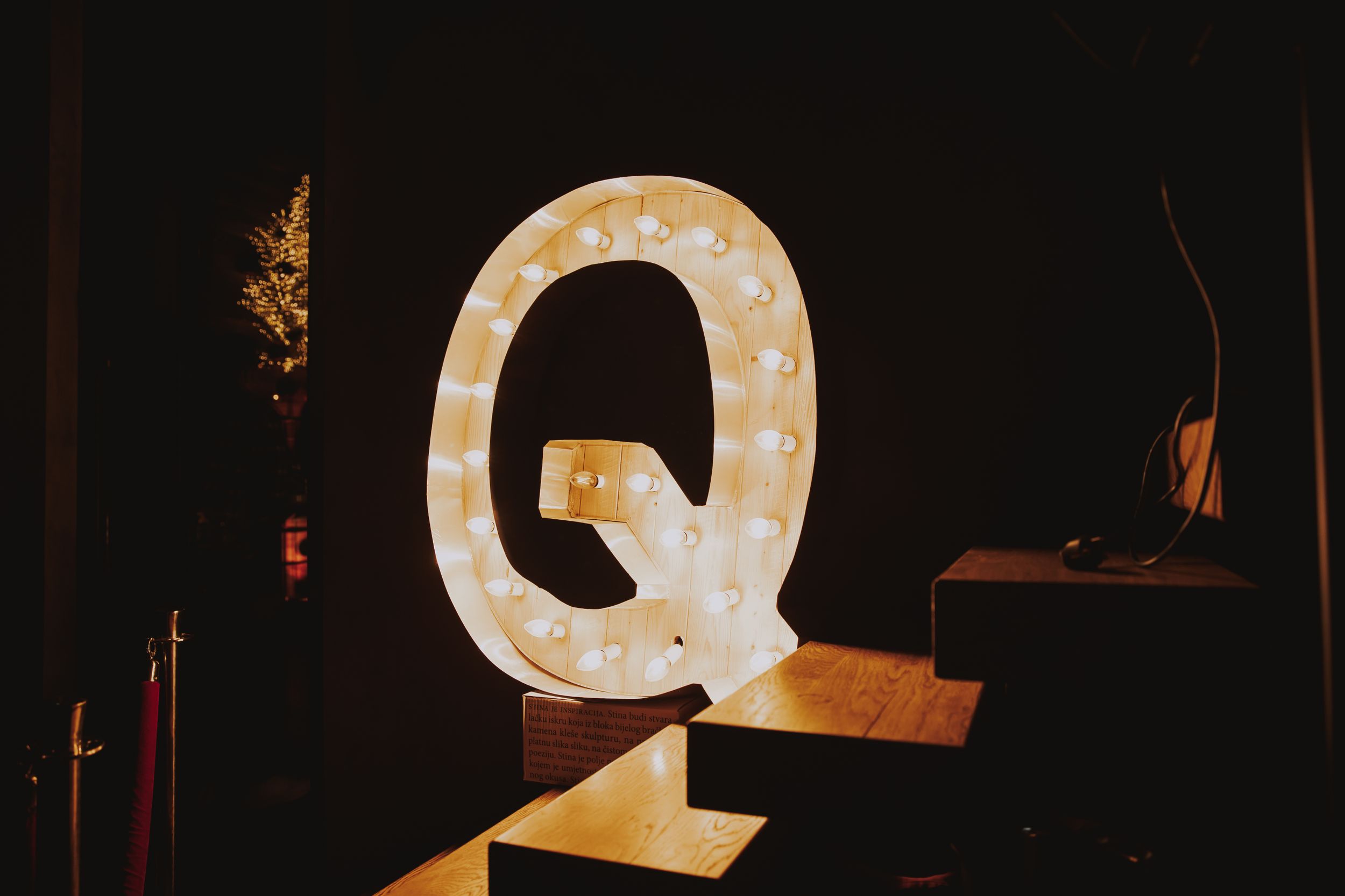 A large illuminated letter Q sign glows against a dark background.