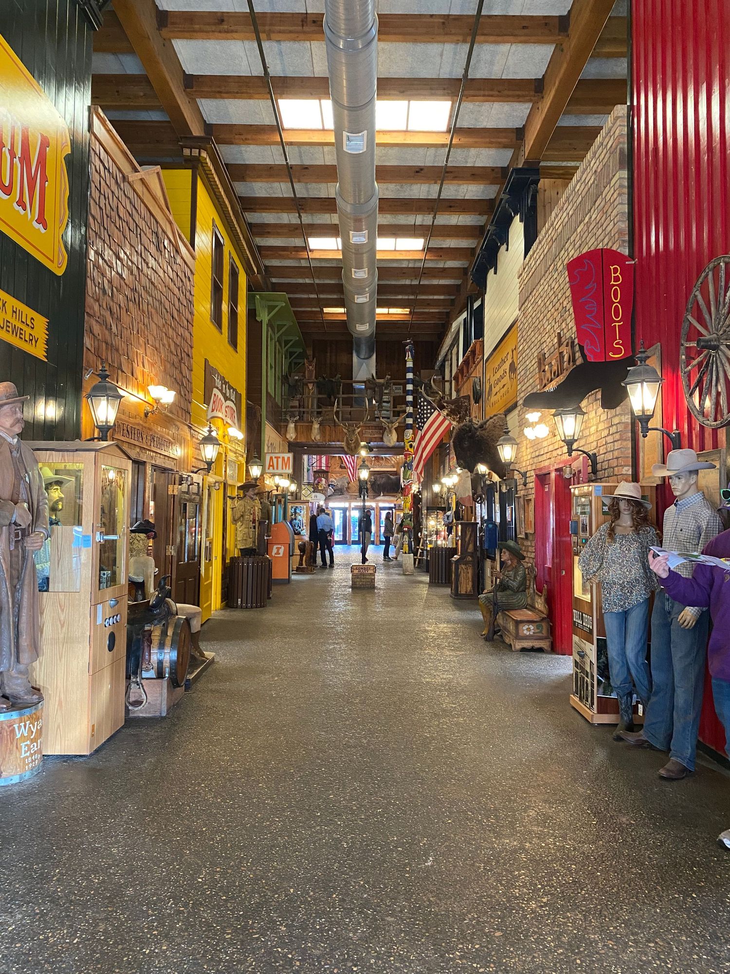 Indoor shopping arcade with colorful storefronts and American flags hanging from wooden beams.