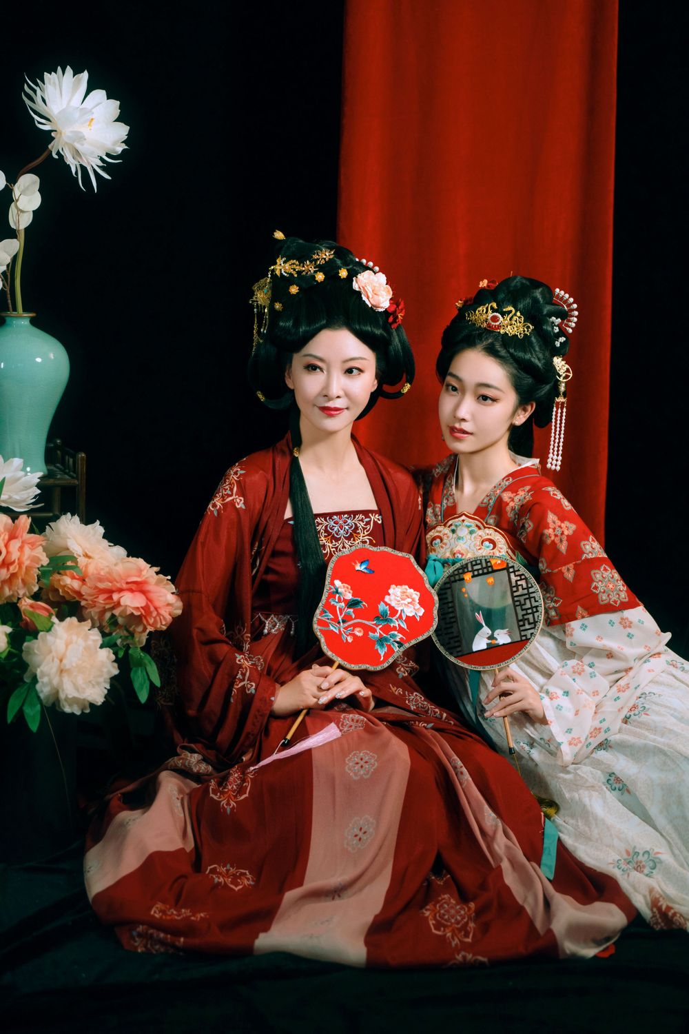 Elegant backlit studio portrait of mother and daughter in Tang Dynasty Hanfu on a swing among wisteria, by Imagine Image Studio.