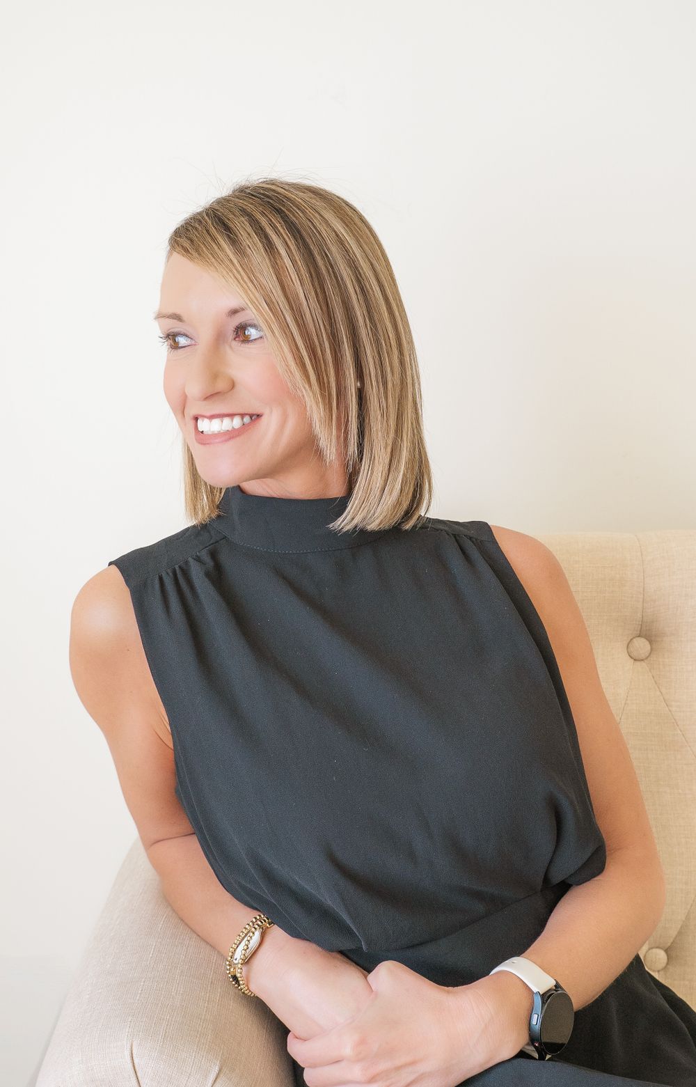 Professional headshot of person in black sleeveless top against neutral background.