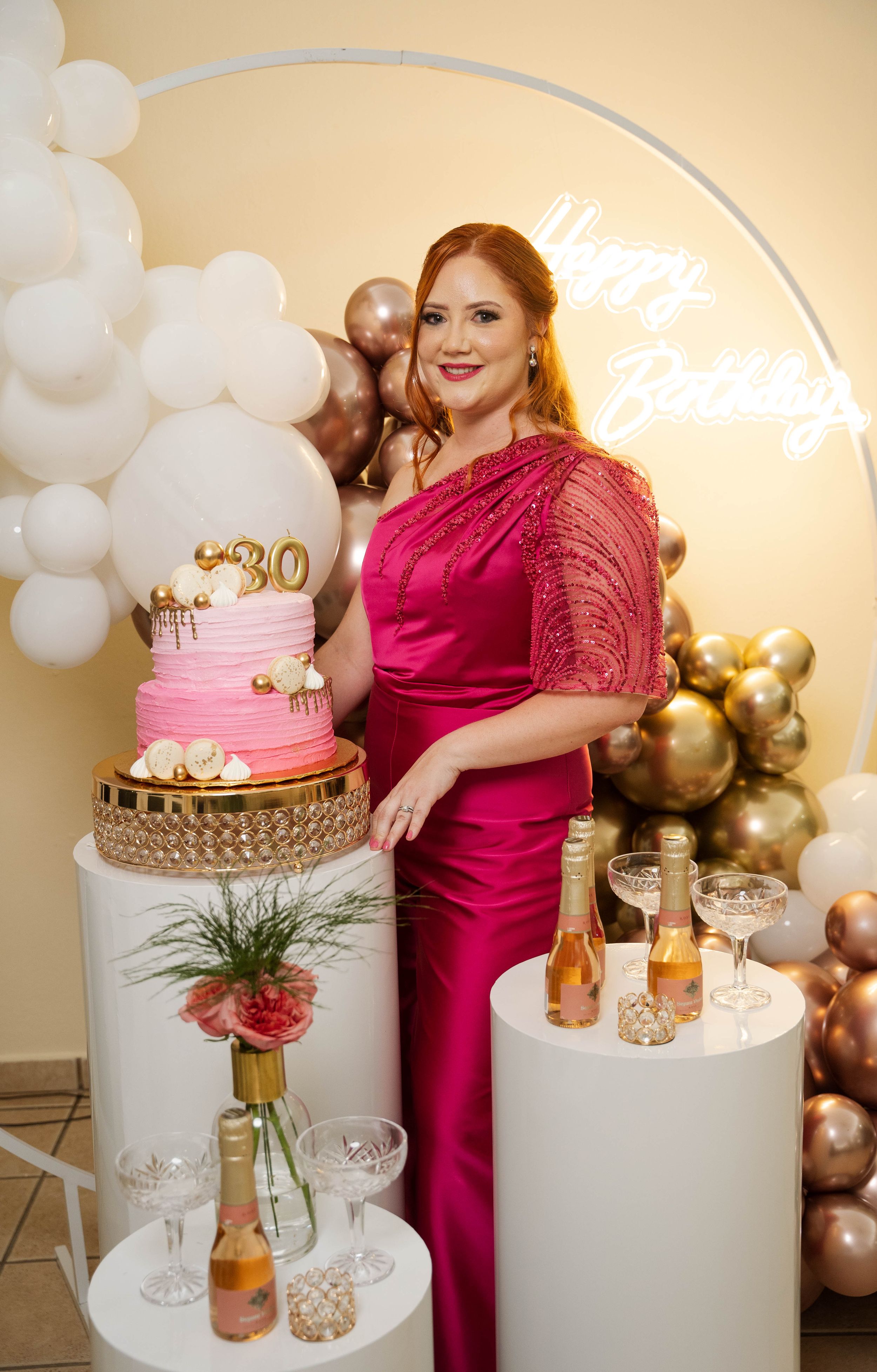 Elegant birthday party display with pink cake, balloon arch, and champagne station.