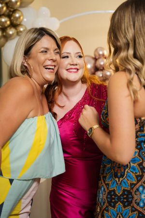 Joyful celebration moment with party guests against gold and white balloon backdrop.