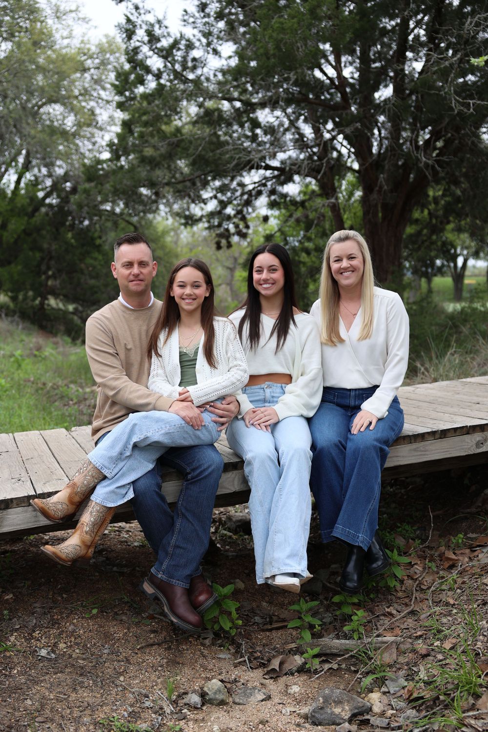 Four people sitting casually together on a wooden platform outdoors.