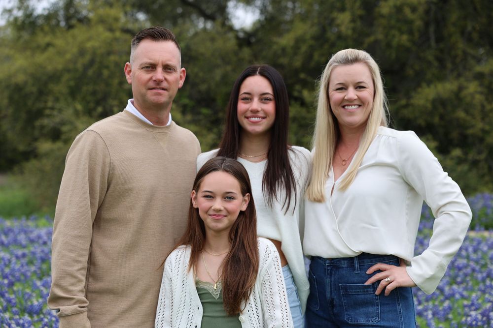 Family portrait in a field of blooming bluebonnets during springtime.