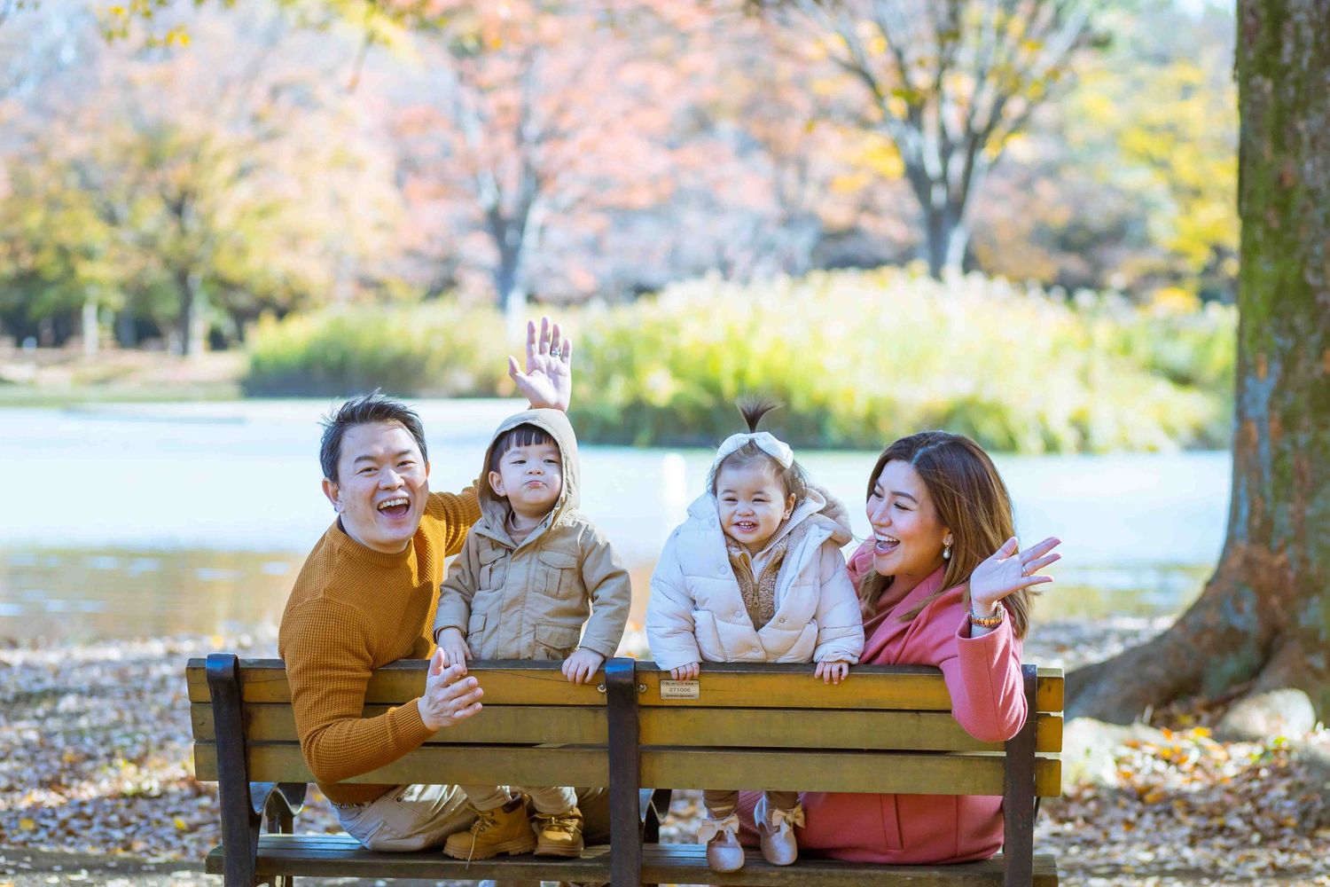 A family sitting on a park bench enjoying autumn scenery together.