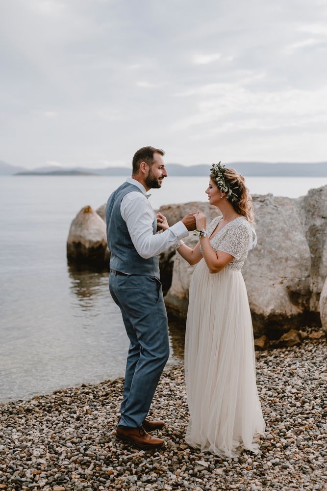Joyful couple dancing on the sandy beach in their wedding attire during their wedding session at Ugljan Island.