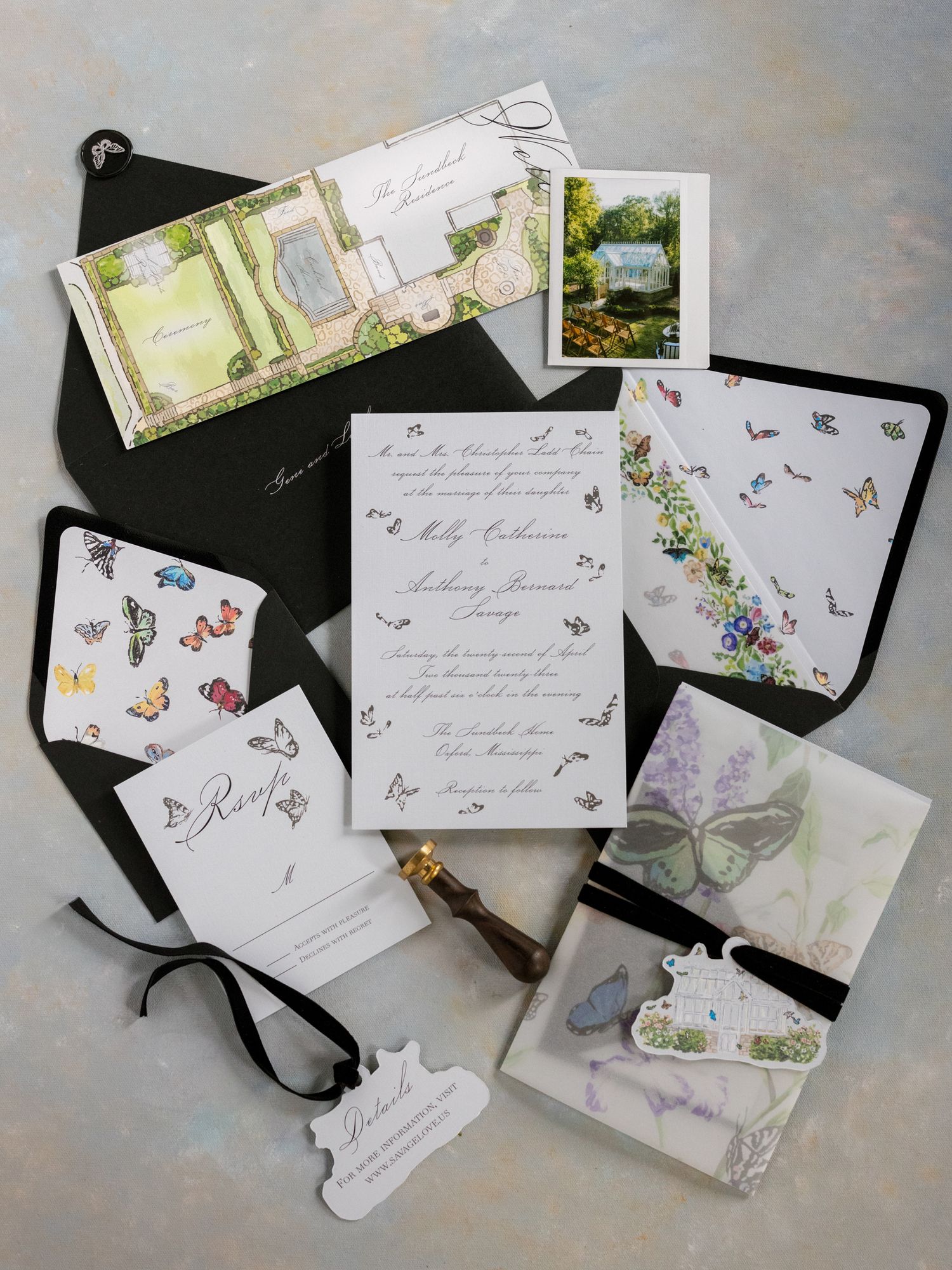 Wedding stationery flat lay with invitation, photographs and butterfly designs.