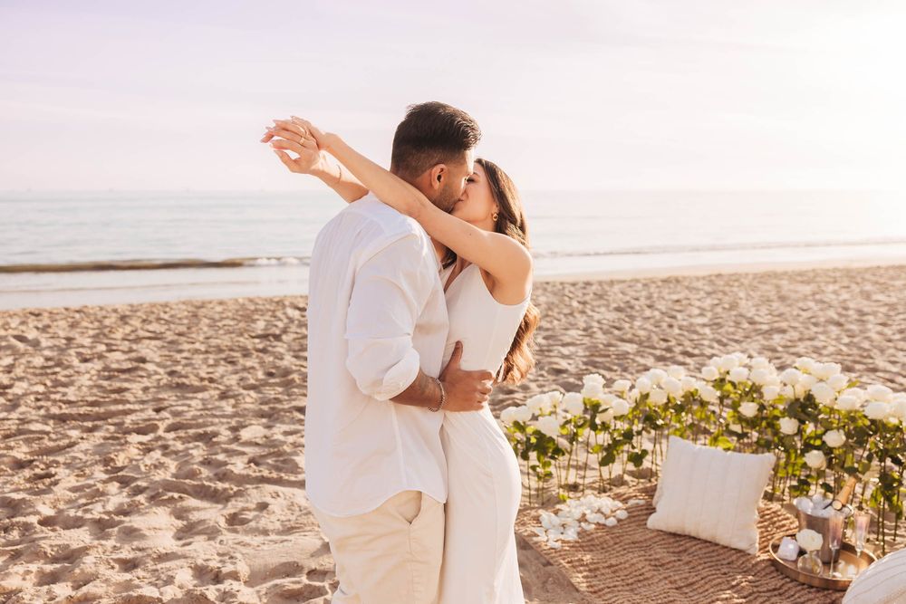A celebratory embrace on the beach after a romantic proposal with flowers.