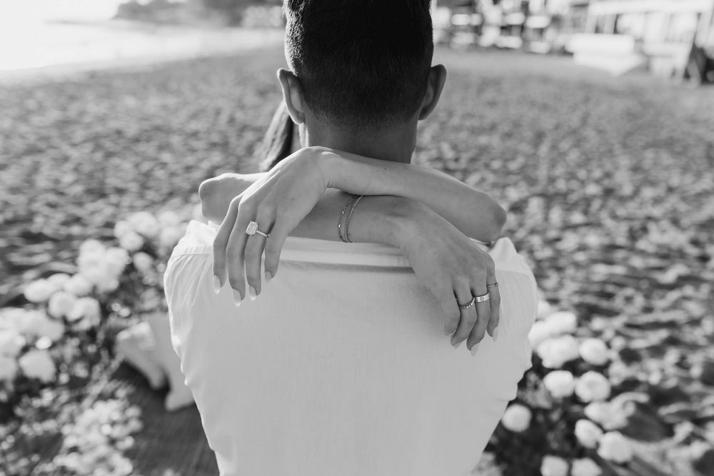 Romantic couple walking hand in hand on a beach at sunset with white clothing and soft lighting.