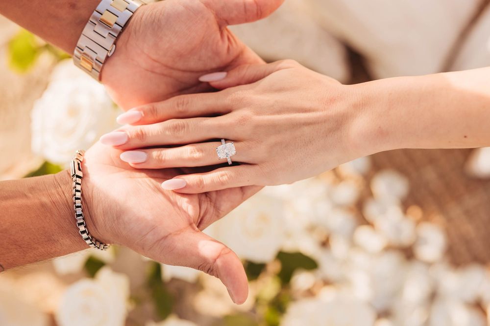 Close-up of hands showing engagement ring with delicate jewelry details.
