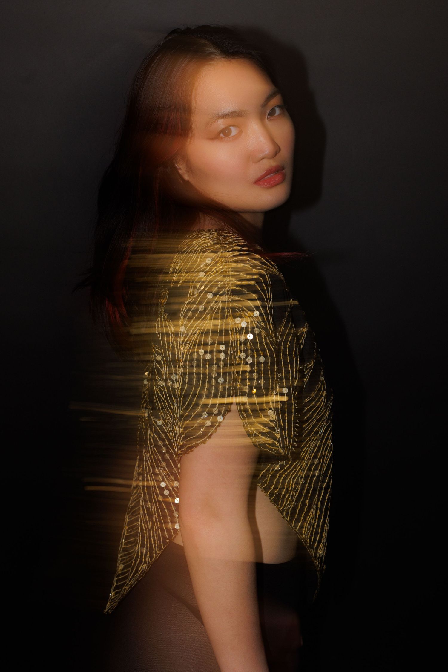 Dramatic studio shot featuring sparkling gold clothing with creative blur effect.