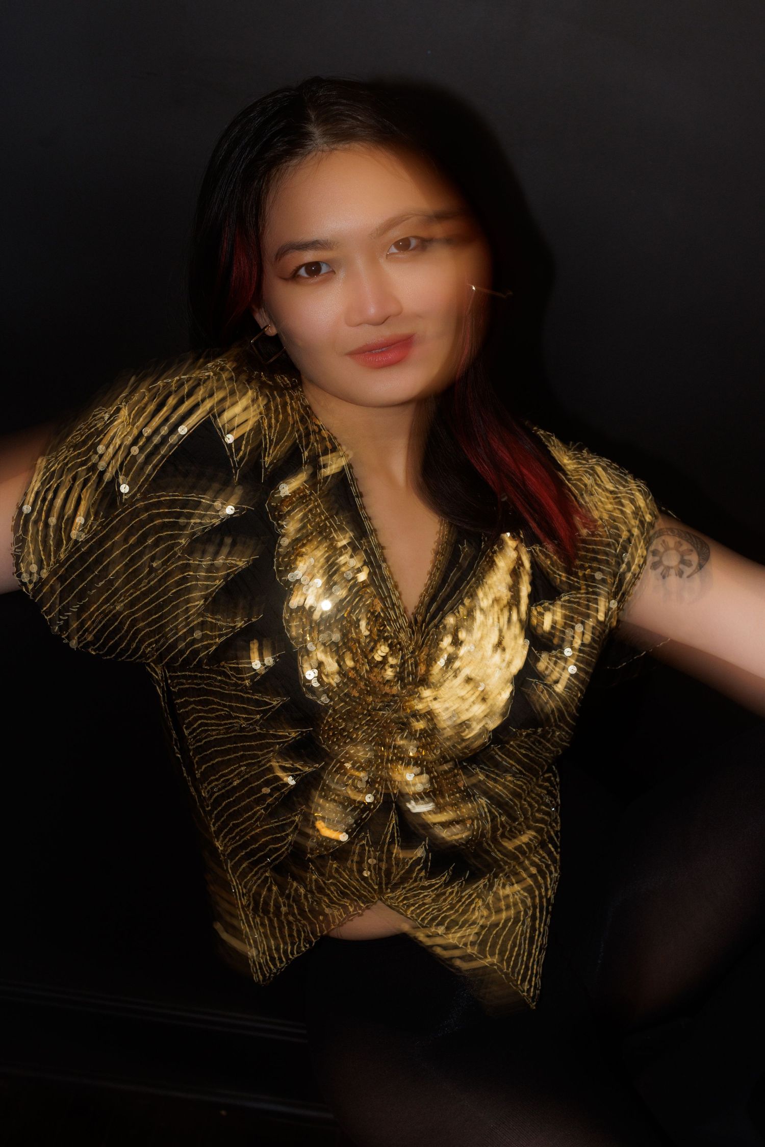 Dynamic portrait featuring a stunning gold sequined top against a dark studio backdrop.
