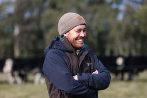 Person wearing beanie and navy jacket smiling outdoors on a sunny day.