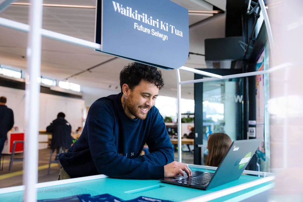 Person working on laptop at a desk in modern office space.