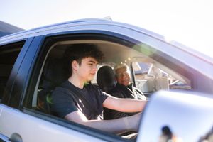 Two people driving in a car together captured through the side window.