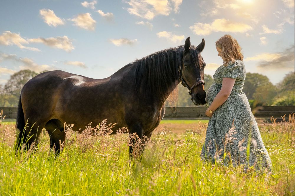 Fotoshoot zwangerschap samen met eigen paarden er bij op het weiland.