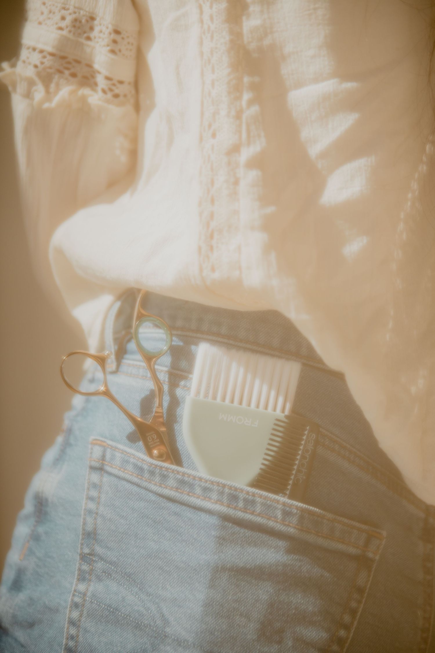 Close-up of hair combs and styling tools in denim pocket with vintage filter effect.