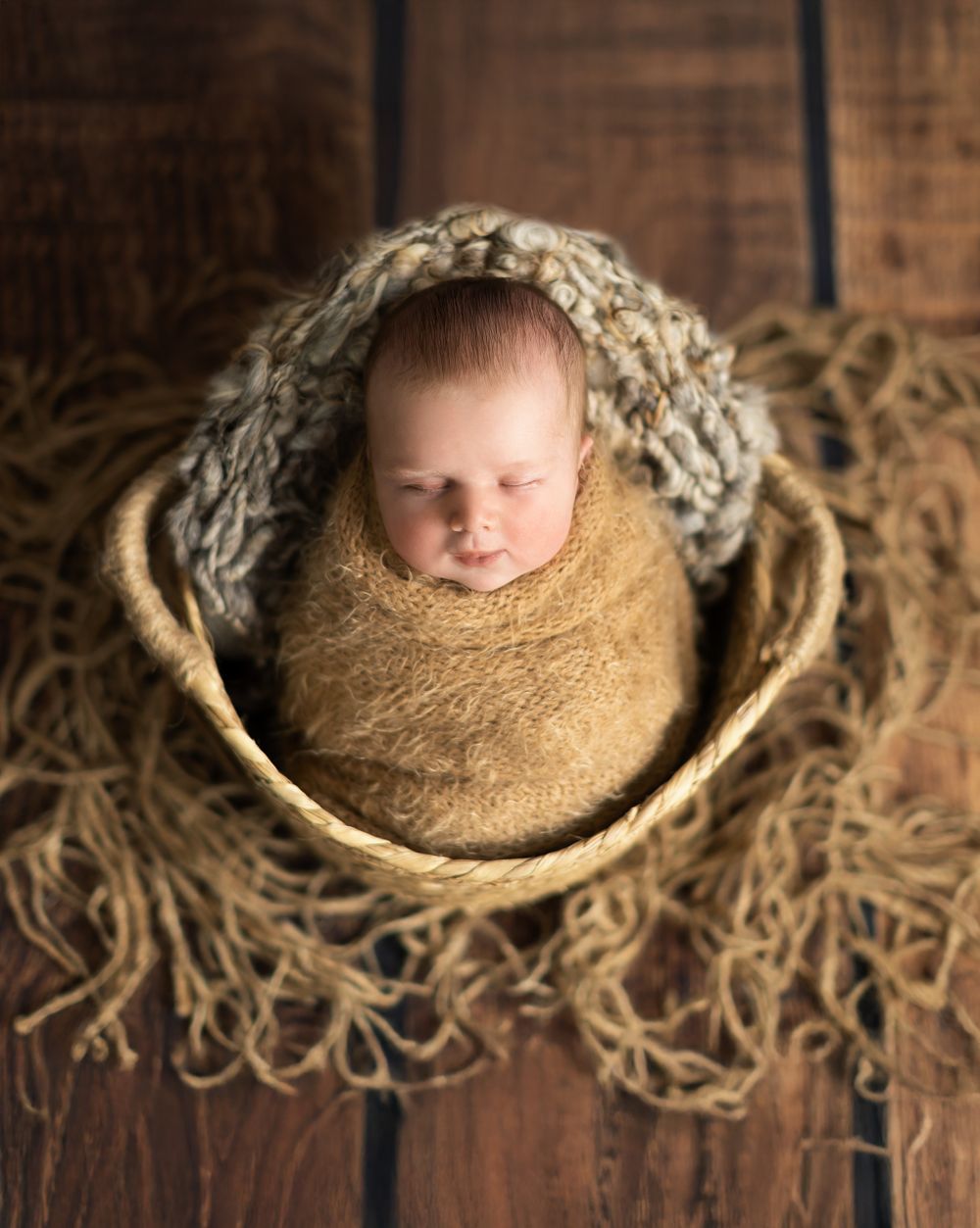 Image of baby boy wrapped in a whicker basket based in my shelly Loxton photography studio in Coventry.