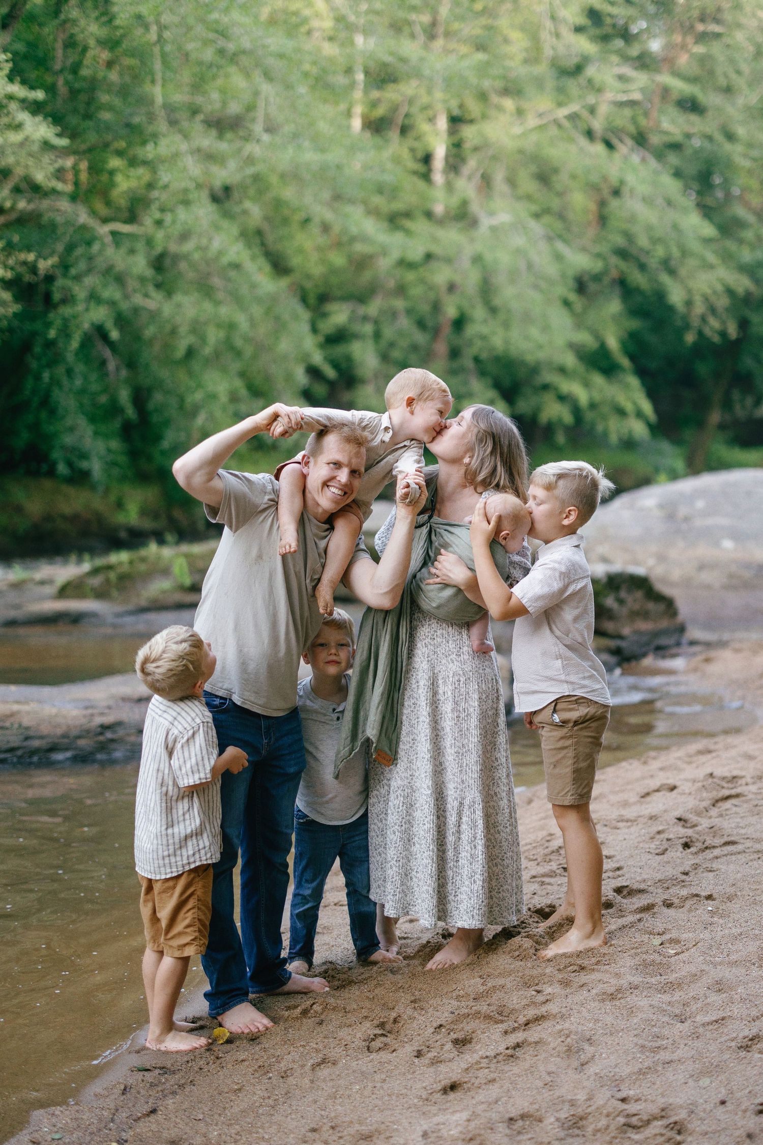 Family having fun together standing on riverbank making silly faces.