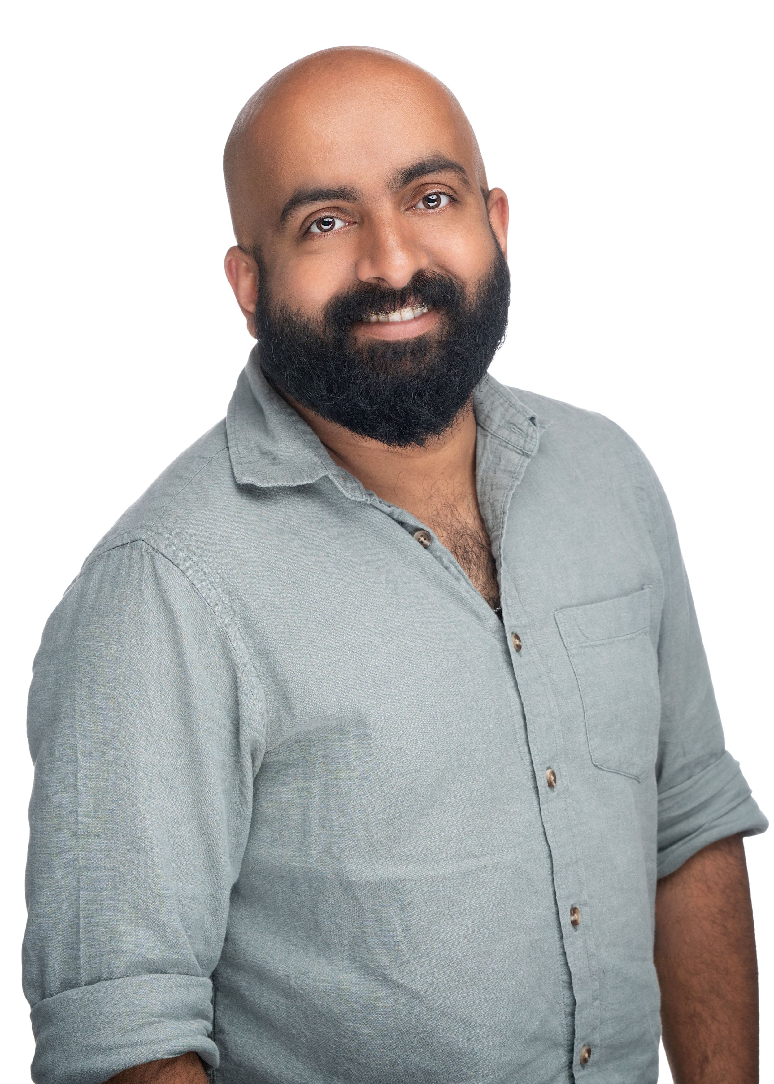 Professional headshot of someone wearing a light gray button-down shirt with rolled sleeves and a full dark beard.