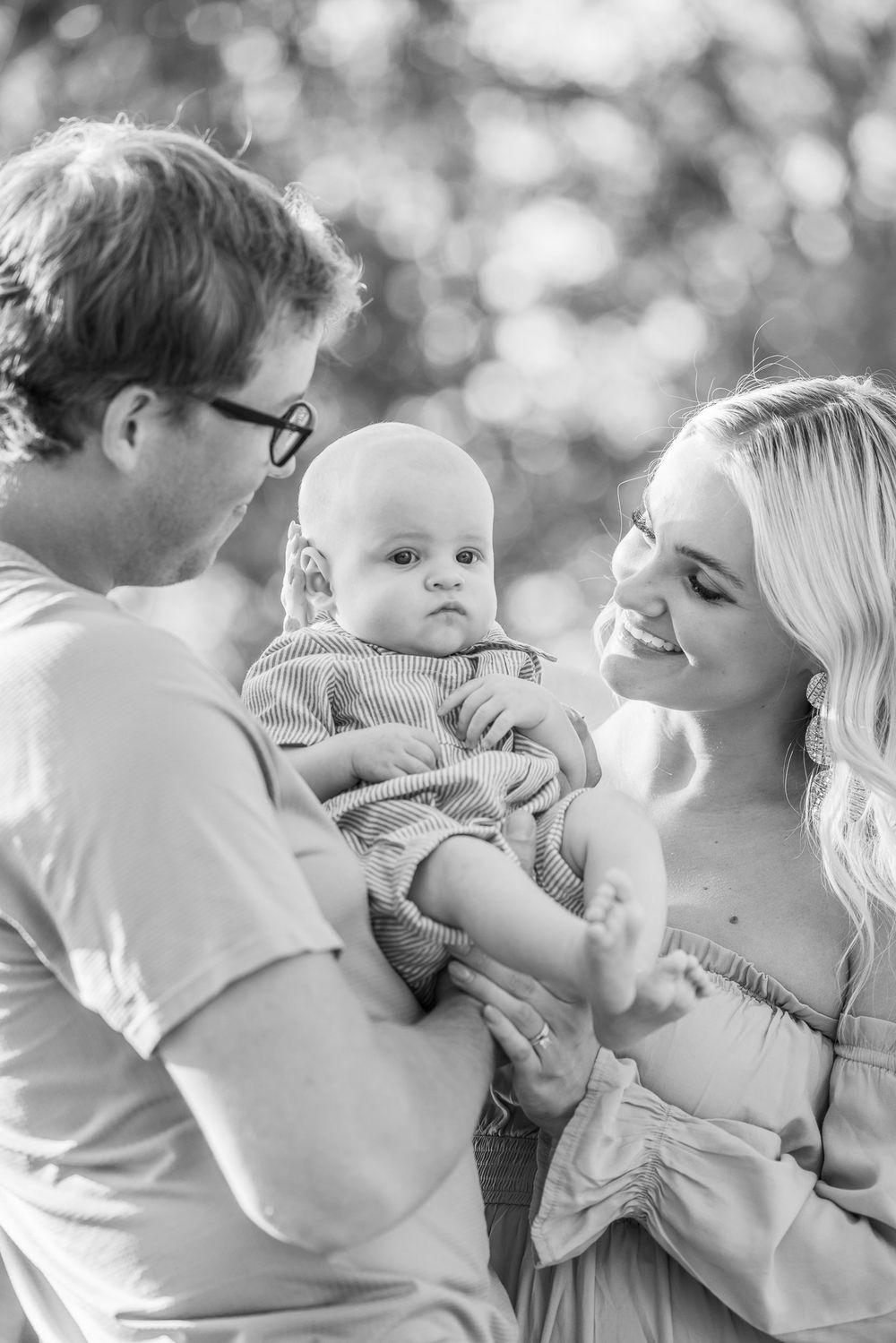 A tender family moment captured in black and white as they hold their baby.
