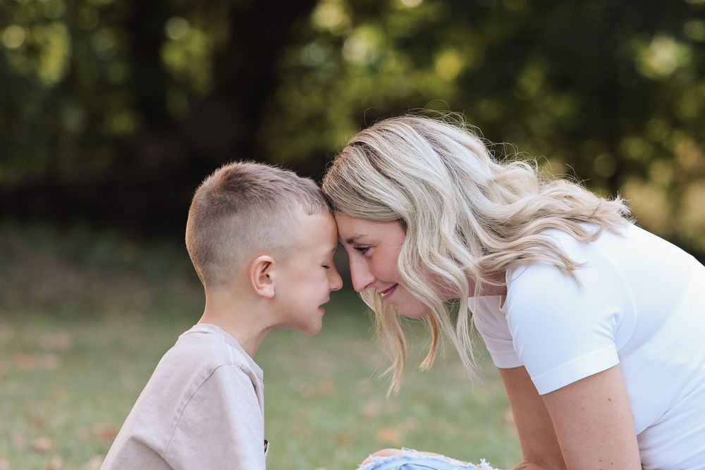 An intimate forehead-touching moment captured in soft natural lighting outdoors.