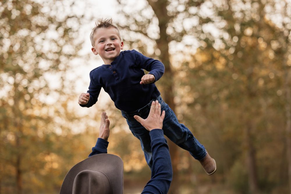 A joyful child leaps playfully through the air on an autumn day in a park.