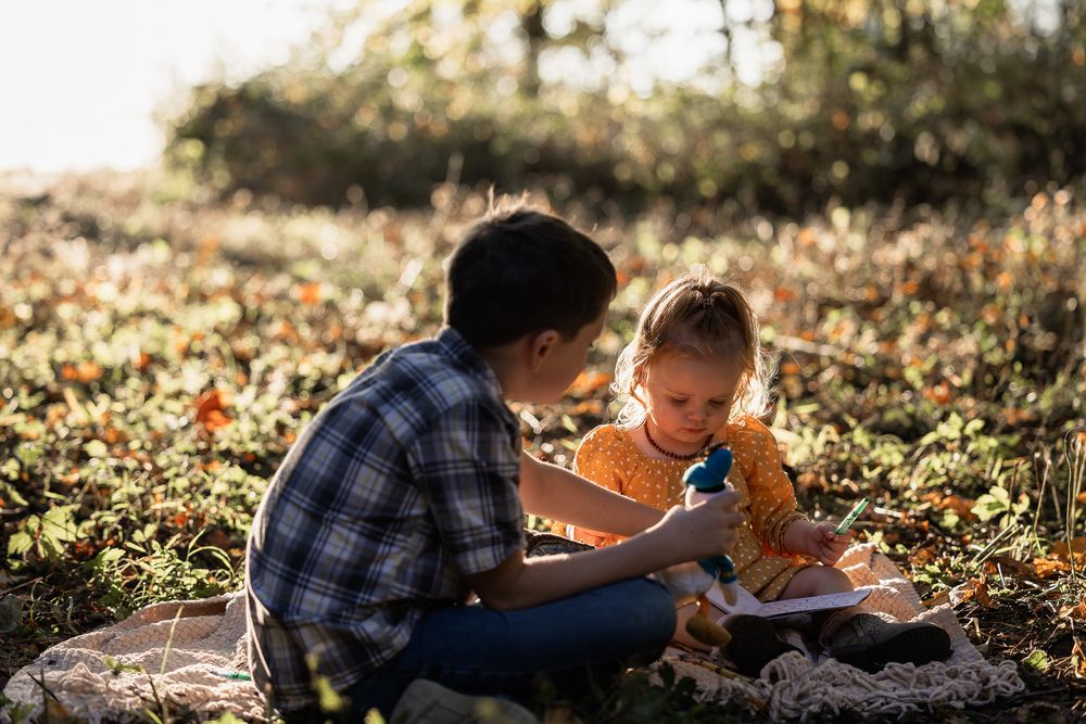 Two people share a quiet reading moment together on a blanket in autumn leaves.