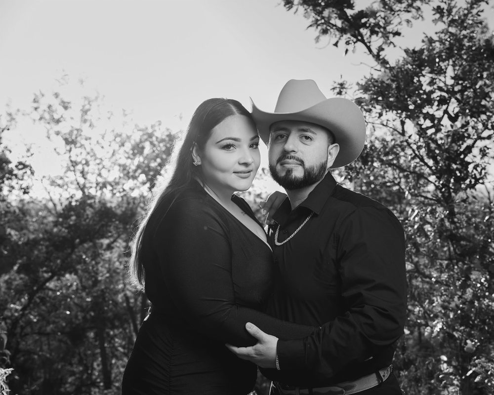 Black and white portrait of couple in western attire against nature backdrop.